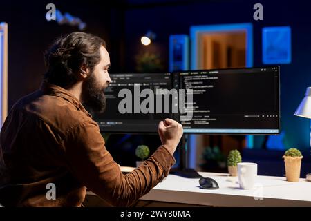 Happy man doing software quality assurance celebrating after reading source code and finding no errors. Cheerful developer excited after inspecting coding on desktop PC, seeing no issues Stock Photo