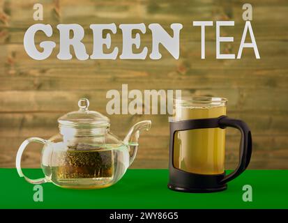 Tea pot and cup of green tea with a wooden background and text up above quoting green tea. Stock Photo