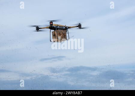 May 5, 2024 - Fort Drum, New York, USA - A TRV 150, Tactical Resupply Vehicle, with a bundle of Meals, Ready-to-Eat flies above a training area on Fort Drum, NY, March 5, 2024. Soldiers with 10th Mountain Division, assisted by Civil Military Innovation Institute, conduct TRV 150, Tactical Resupply Vehicle, training on Fort Drum, New York, March 5, 2024. This operation was held in order to innovate how resupply missions are conducted with another availability on how that mission can be executed. Being able to resupply Soldiers with support equipment without having any Soldiers at risk of danger Stock Photo