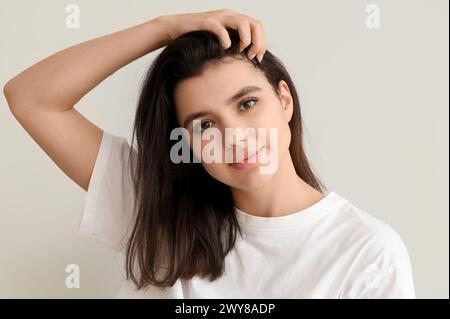 Young woman with dandruff problem examining her hair on white background Stock Photo