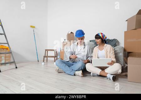 Young couple with paint color palettes using laptop during repair in their new house Stock Photo