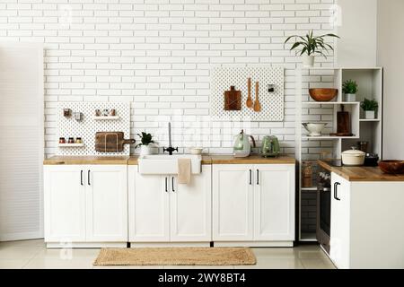 Stylish light kitchen with pegboards and kitchenware Stock Photo