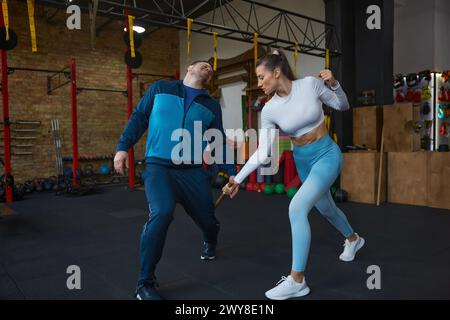 Young woman fighting with stick practicing Bo-Jutsu or Kung Fu with trainer Stock Photo