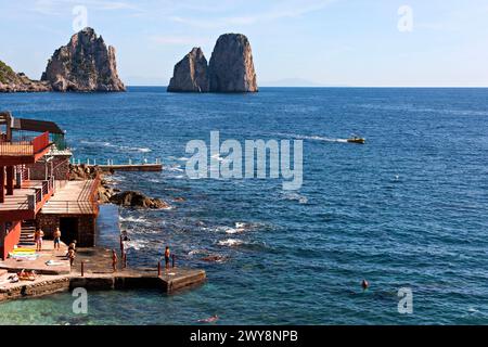 Sunbathers and swimmers with the  Faraglioni Rocks in background, Marina Piccola, Capri, Campania, Italy, Europe Stock Photo