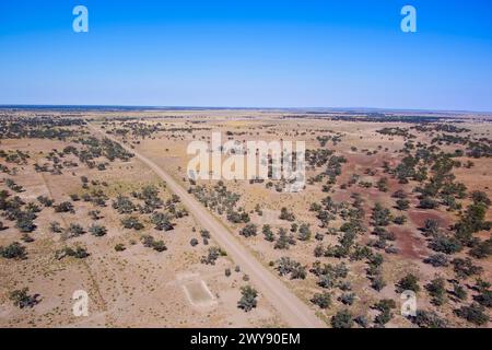 Aerial view of a straight dirt road cutting through a sparsely vegetated desert landscape Stock Photo