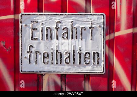 White, old sign Keep driveway clear on a red garage door, Germany Stock Photo