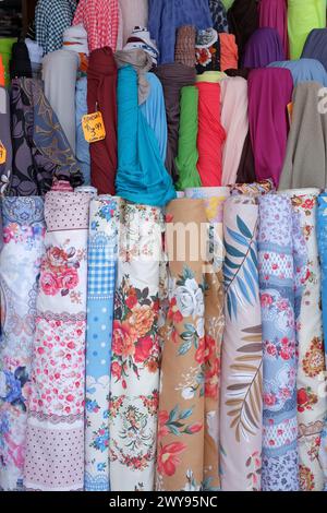 Fabric displayed in rolls of bright colours and rolls of floral patterns in a dressmaking store on the streets of Cabramatta, Western Sydney Stock Photo