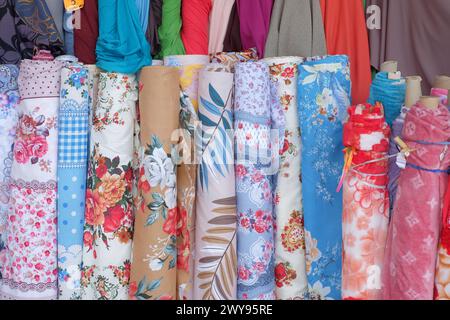 Colourful rolls of fabrics with floral patterns displayed at the front of a dressmaking shop on the streets of Cabramatta, Western Sydney Stock Photo