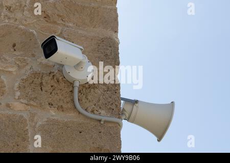 Surveillance Camera and Loudspeaker on Stone Wall Stock Photo