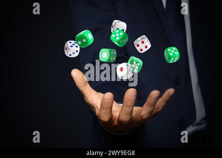 Businessman throwing dice on black background, closeup Stock Photo