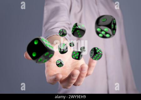 Man throwing black dice on grey background, closeup Stock Photo