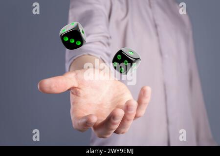 Man throwing black dice on grey background, closeup Stock Photo