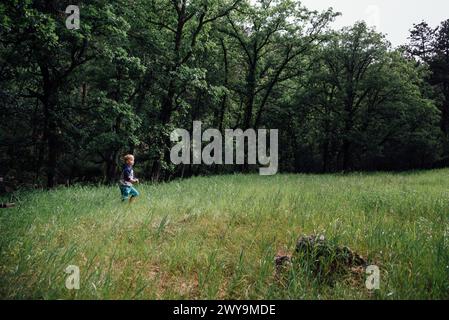 Small boy running in clearing in forest in summer Stock Photo