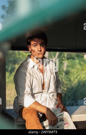 adult italian man sitting in an office room with newspaper in hand Stock Photo