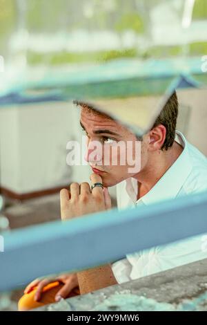young handsome male looking out of camera through broken glass Stock Photo