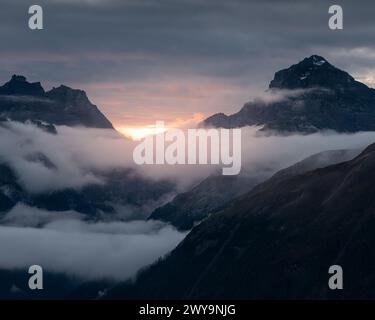 A dramatic sunset over mountains shrouded in clouds Stock Photo