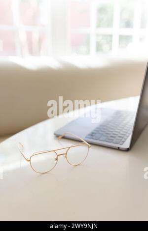Glasses on table with laptop in a bright room Stock Photo