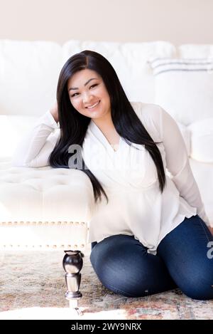 Joyful asian woman sitting on floor casually and smiling Stock Photo