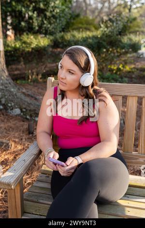 Woman with headphones using phone outdoors Stock Photo