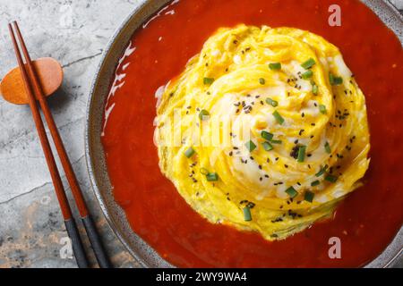 Swirl omelette tornado with fried rice and hot pepper sauce close-up in a plate on the table. Horizontal top view from above Stock Photo