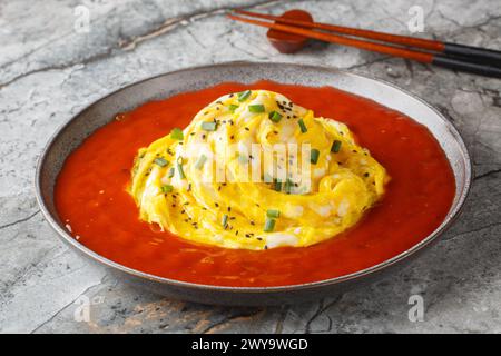 Tornado omelette on top of fried rice with sesame seeds, green onions and hot pepper sauce close-up in a plate on the table. Horizontal Stock Photo