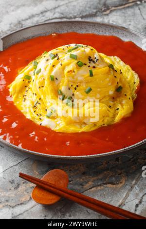 Korean tornado omelette over fried rice and hot sauce closeup on the plate on the table. Vertical Stock Photo