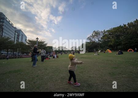 A joyful scene of children playing with soap bubbles and families enjoying a sunny day at Huashan Park Stock Photo