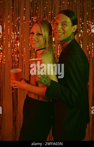 A man and woman in casual attire stand side by side at a vibrant rave party venue Stock Photo
