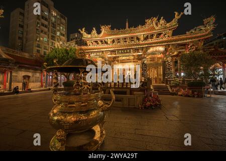 An intricately decorated Longshan temple at night filled with flowers and golden statues Stock Photo