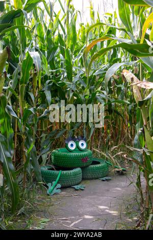 A vertical shot of recycled tire frog art installation in a cornfield Stock Photo