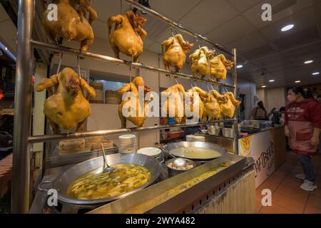 A woman serving traditional Chinese dishes at a food stall in the streets of Jiufen Stock Photo