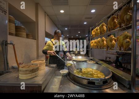 A woman serving traditional Chinese dishes at a food stall in the streets of Jiufen Stock Photo