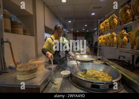 A woman serving traditional Chinese dishes at a food stall in the streets of Jiufen Stock Photo