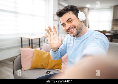 Selfie of brown-haired smiling man with white headphones Stock Photo