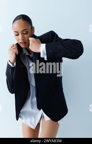 Young African American woman in black jacket and white shirt exudes confidence in studio setting. Stock Photo