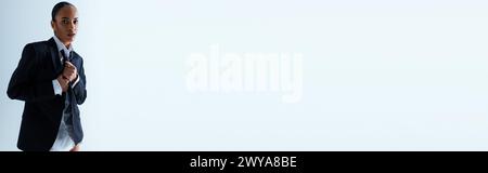 Young black woman in pinstripe suit and tie standing against white background Stock Photo