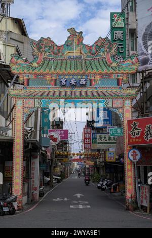 A colorful, elaborately decorated archway with traditional motifs leading into a quaint Taiwanese street in the city of Chiayi Stock Photo