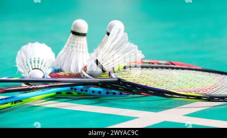 White badminton shuttlecocks and badminton rackets on green floor indoor badminton court Stock Photo