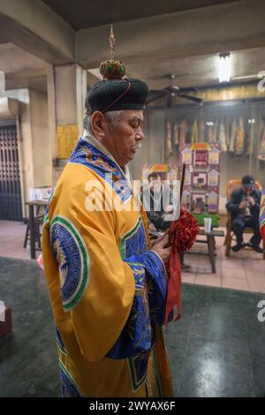 A traditional shaman performing a ritual with offerings to the ancestors on an altar in Donggyue Hall temple Stock Photo