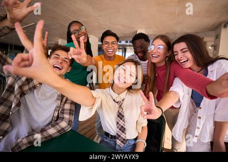 Portrait group of cheerful young multiracial university students posing smiling doing peace gesture Stock Photo