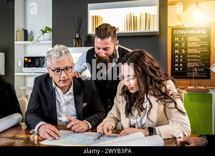 Collaborative team analyzing strategy in modern coworking space. Experienced leader guides young professionals through project details. A blend of gen Stock Photo