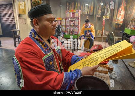 A traditional shaman performing a ritual with offerings to the ancestors on an altar in Donggyue Hall temple Stock Photo