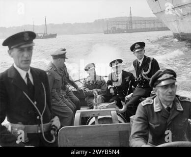 THE NAVY TAKES OVER AT KIEL. 6 TO 12 MAY 1945, THE GERMAN NAVAL BASE AT KIEL AFTER THE ROYAL NAVY HAD TAKEN IT OVER. - Rear Admiral H T Baillie-Grohman, CB, DSO, OBE, Flag Officer in Charge, Kiel (seated in background) touring the harbour in a German naval craft with General E H Barker, 8th Corps Commander, and Brigadier Matthews. Note the German coxswain (right). , Stock Photo