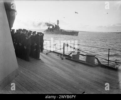 SCENES ON BOARD A BATTLESHIP AT SEA. 1940 OR 1941, ON BOARD HMS RODNEY. - Battlecruiser leaving harbour. Men of the battleship line the deck in the foreground. , Stock Photo