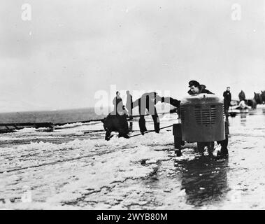 Fleet Air Arm pilots and observers aboard HMS Vindex clear snow from the flight deck using a small motor vehicle called a doodle-bug during an Atlantic convoy in March 1944. Stock Photo