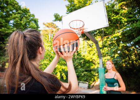 A girl is holding a basketball and is shooting during a game. Stock Photo