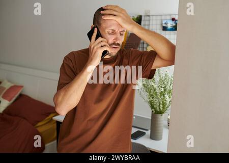 Mature man suffering from severe headache calling his doctor Stock Photo