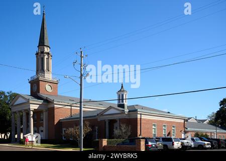 The First Presbyterian Church of Pensacola rises, a beacon of faith with a red-brick embrace, reaching for the heavens through Pensacola's serene blue Stock Photo