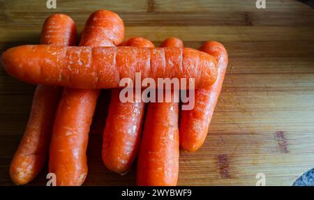 Unpeeled carrots on a wooden chopping board Stock Photo