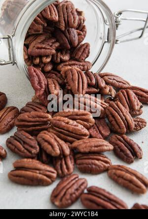 Raw healthy pecan nuts snack in glass jar on white kitchen table. Stock Photo